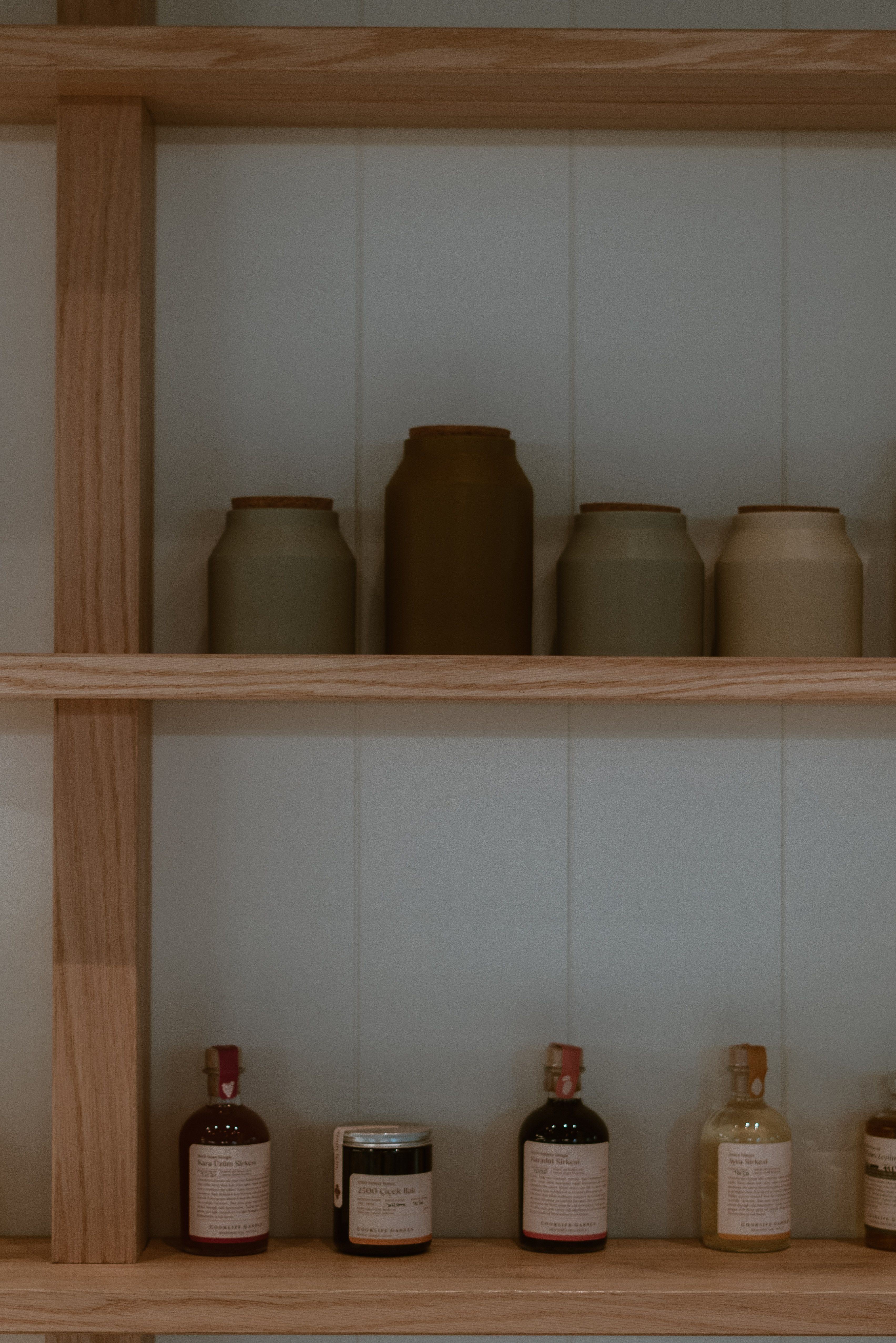 Storage containers lined up on a pale pantry shelf
