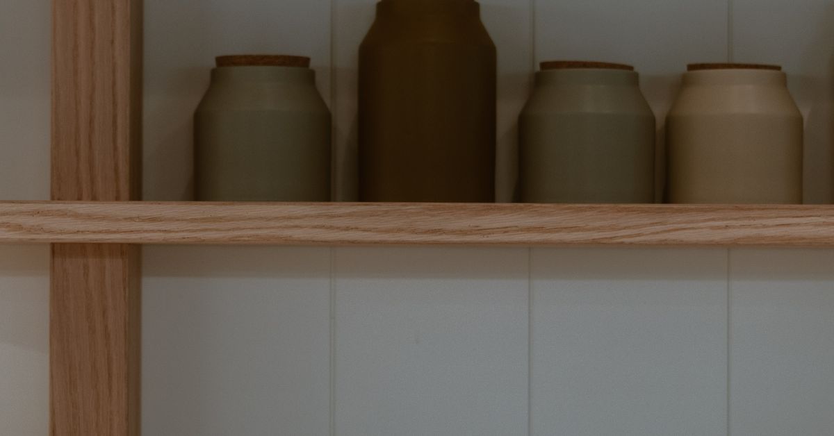 Storage containers lined up on a pale pantry shelf