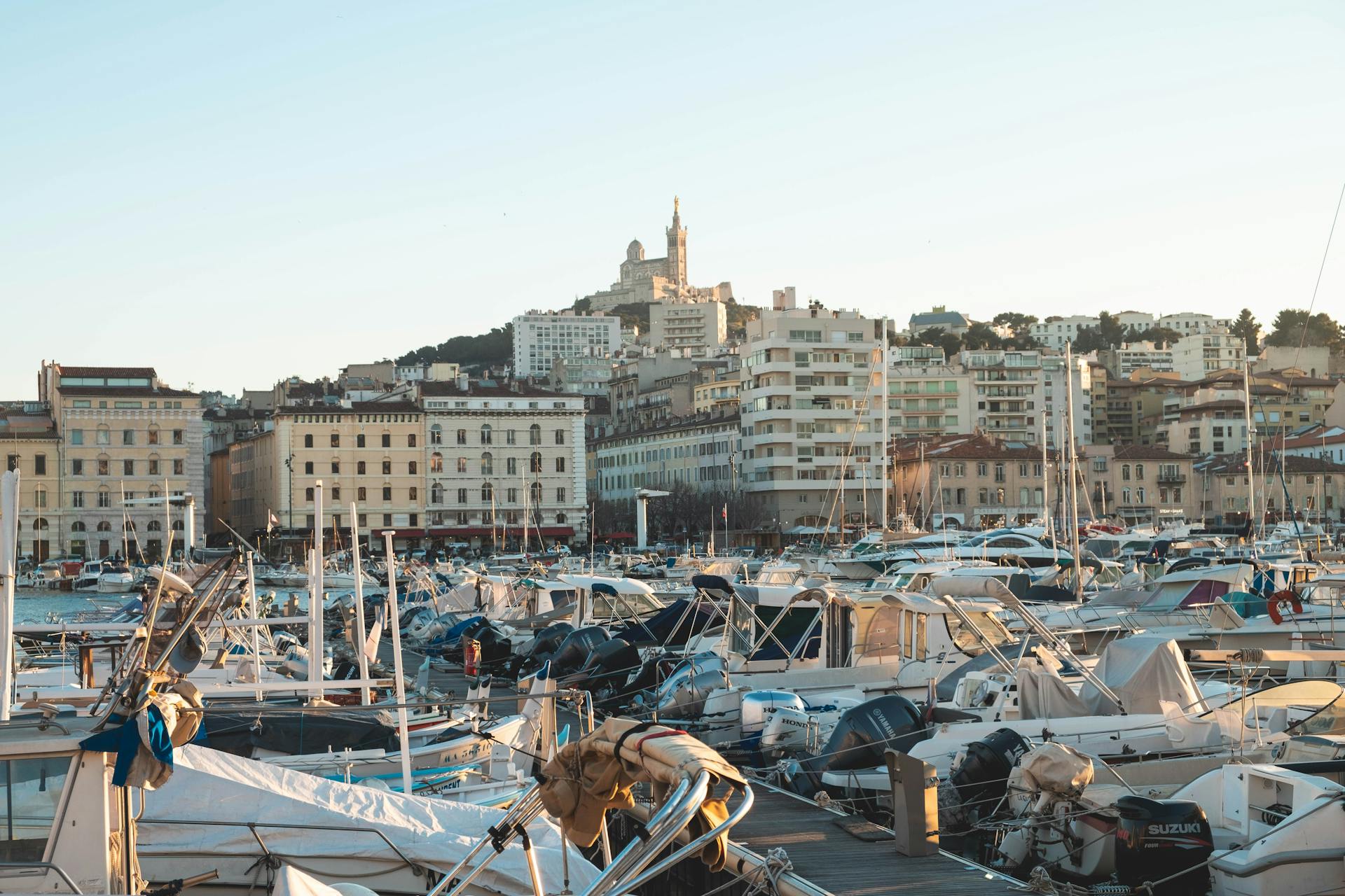 Explore the vibrant Vieux Port marina in Marseille with moored boats and historic architecture under a warm sunset.