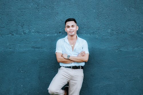 Free Man in White Shirt with Arms Crossed Posing on a Blue Wall Stock Photo