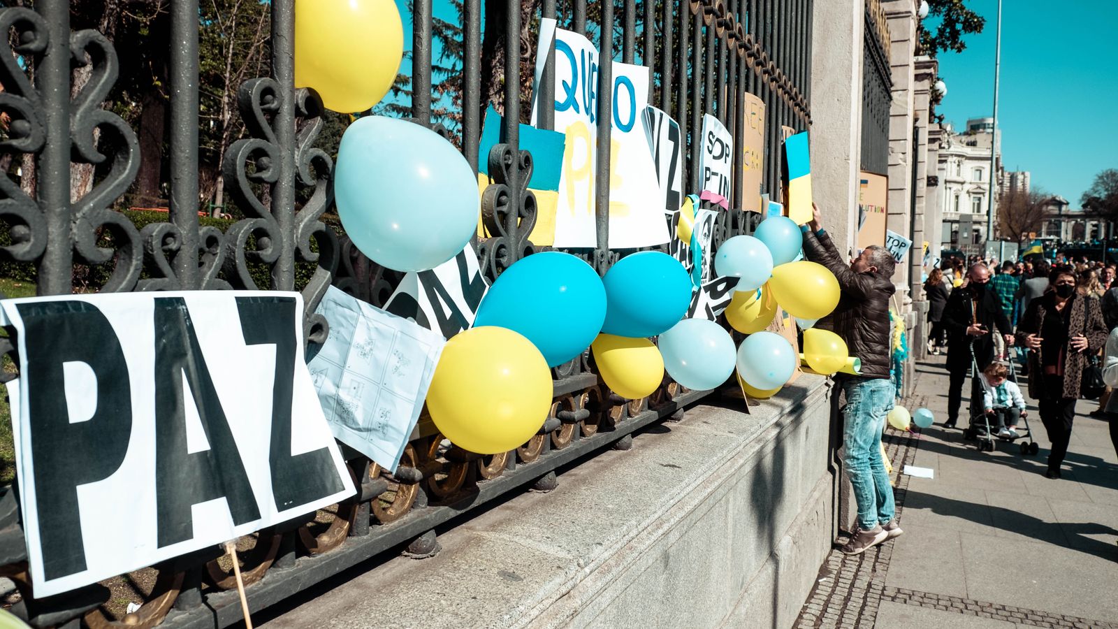 Colorful balloons and signs advocating for peace during a protest in Madrid, Spain.