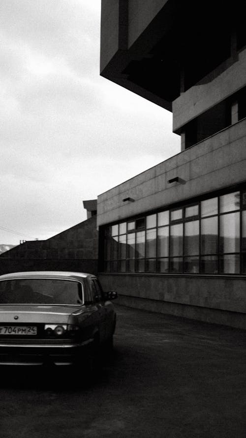 Grayscale Photo of Car Parked Beside the Building