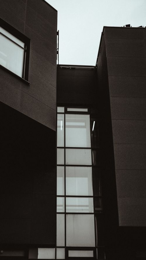 Free Low angle shot of a modern building facade with glass panels and geometric design, showcasing contemporary architecture. Stock Photo