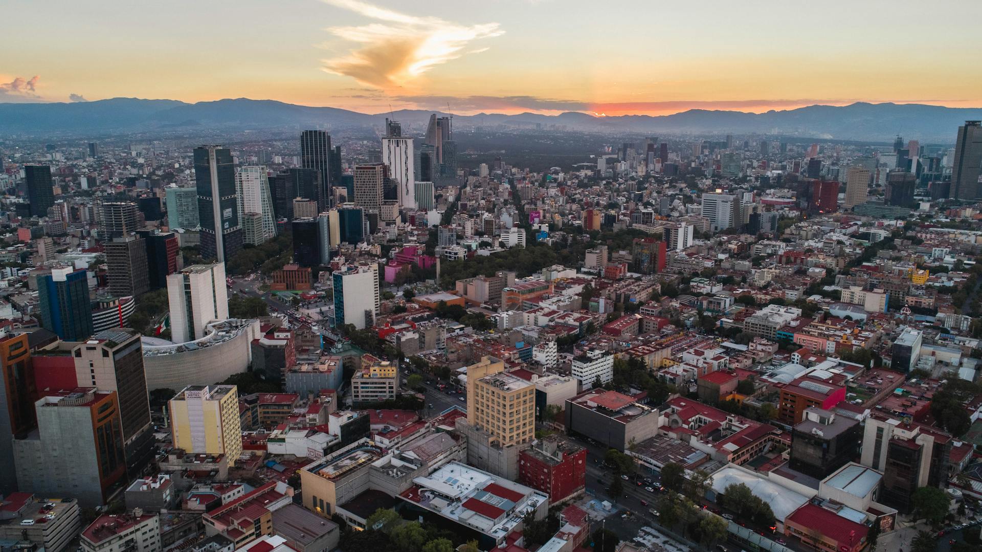 Stunning aerial view of Mexico City skyline during sunset, showcasing vibrant urban landscape.