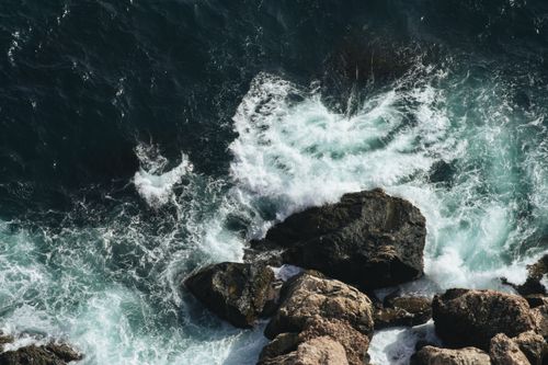 Free Aerial view of ocean waves crashing against a rocky shoreline, showcasing nature's power. Stock Photo