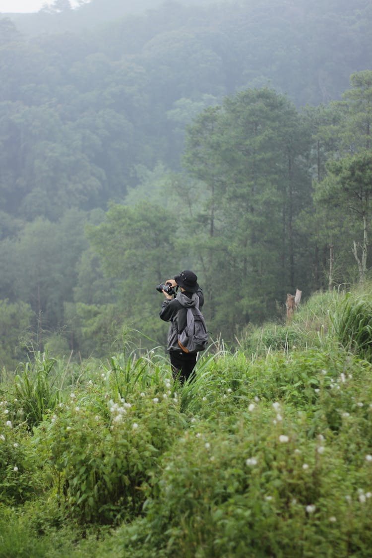 Person Standing In Thick Grass Taking Photograph