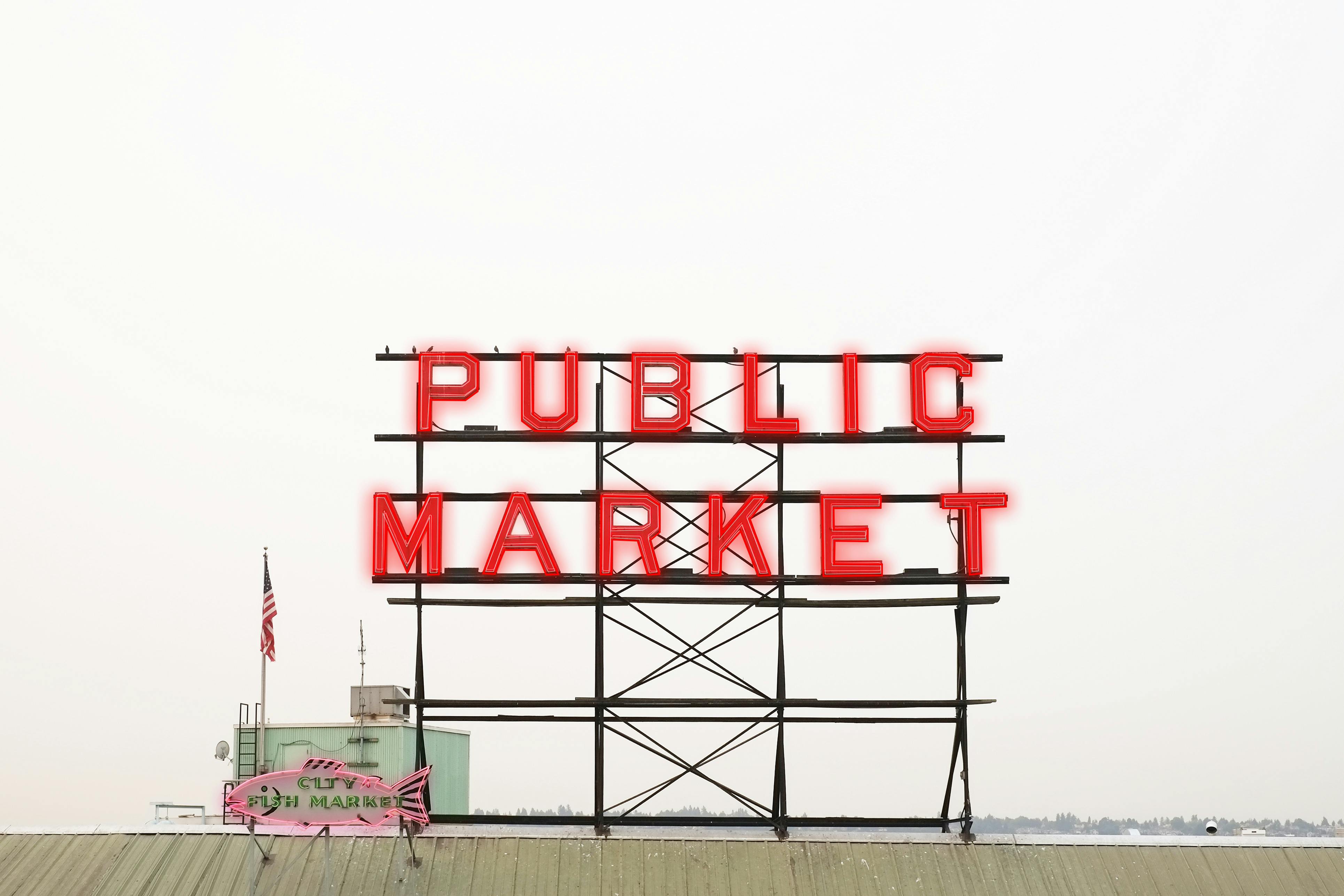 Vibrant neon public market sign in Seattle against a clear sky.