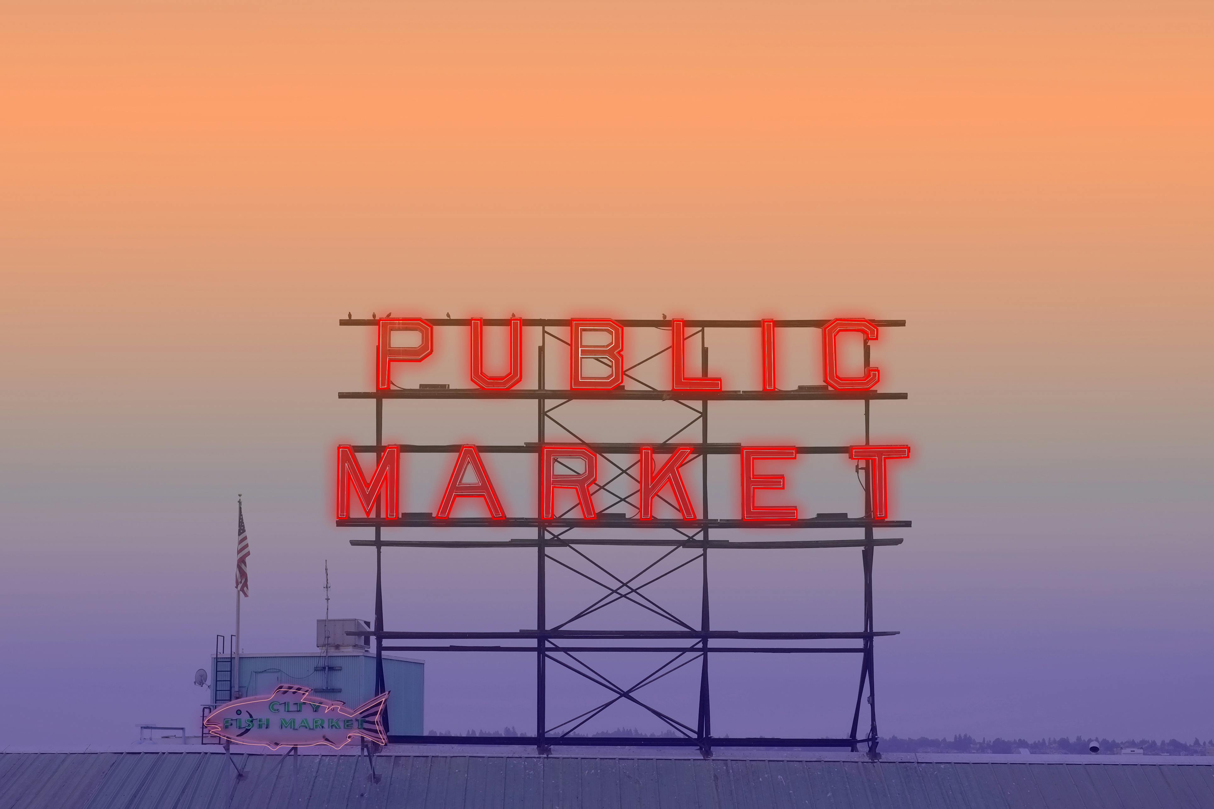 Iconic neon sign of Seattle's Pike Place Market against a vibrant sunset sky.