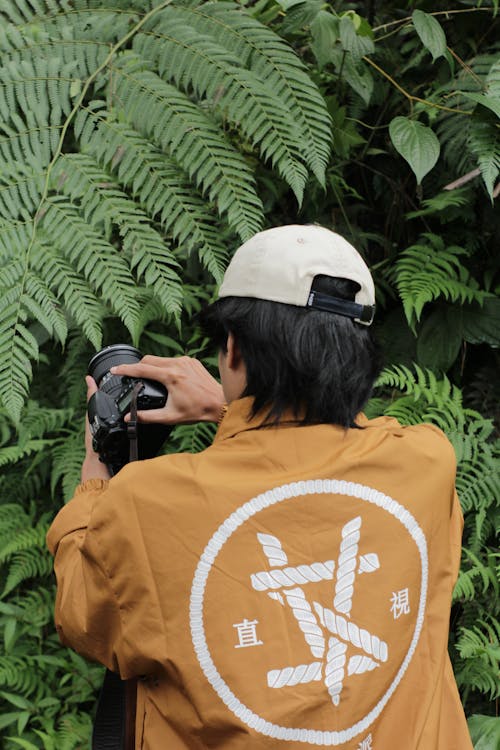 A Person in Brown Jacket Taking Photo of Green Leaves