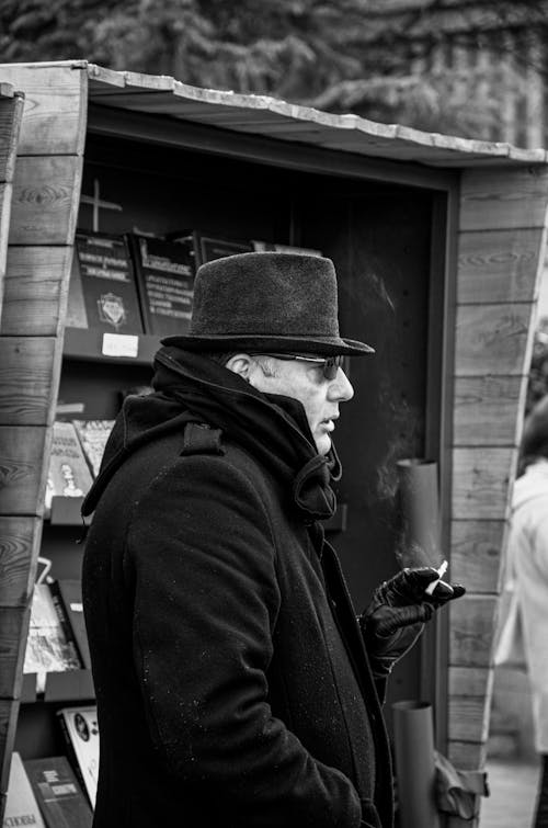 Grayscale Photo of a Man in a Coat Smoking a Cigarette