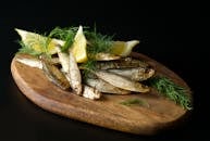 An Anchovies and Sliced Lemons on a Wooden Board
