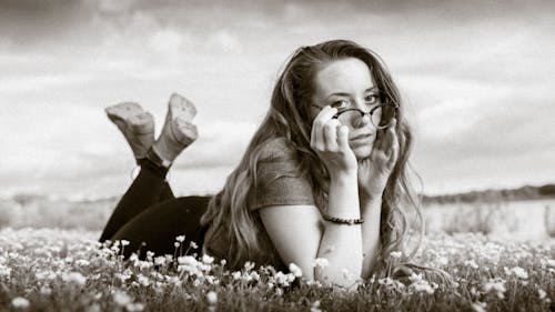 Free A Grayscale Photo of a Woman Lying on a Flower Field Stock Photo