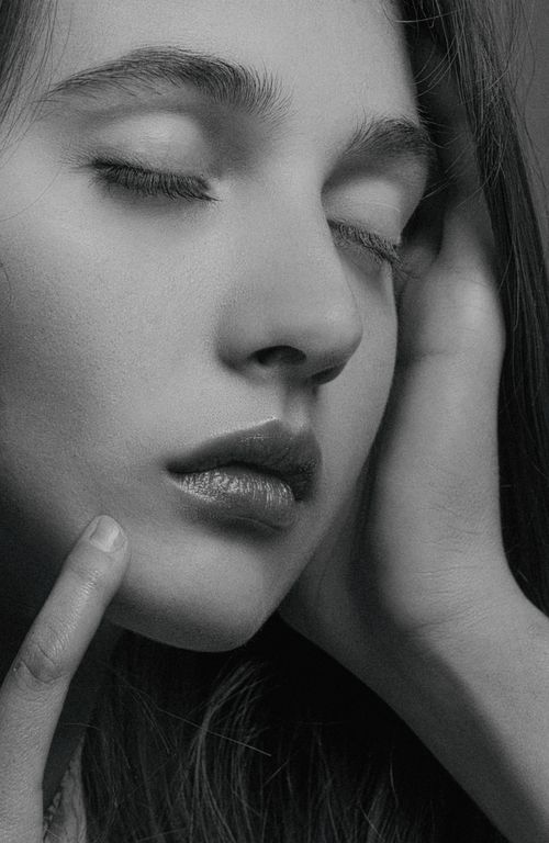 Free Close-up portrait of a caucasian woman with eyes closed, in grayscale, touching her face gently. Stock Photo
