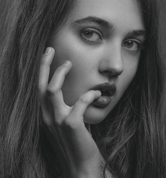 Captivating black and white close-up portrait of a woman posing thoughtfully.