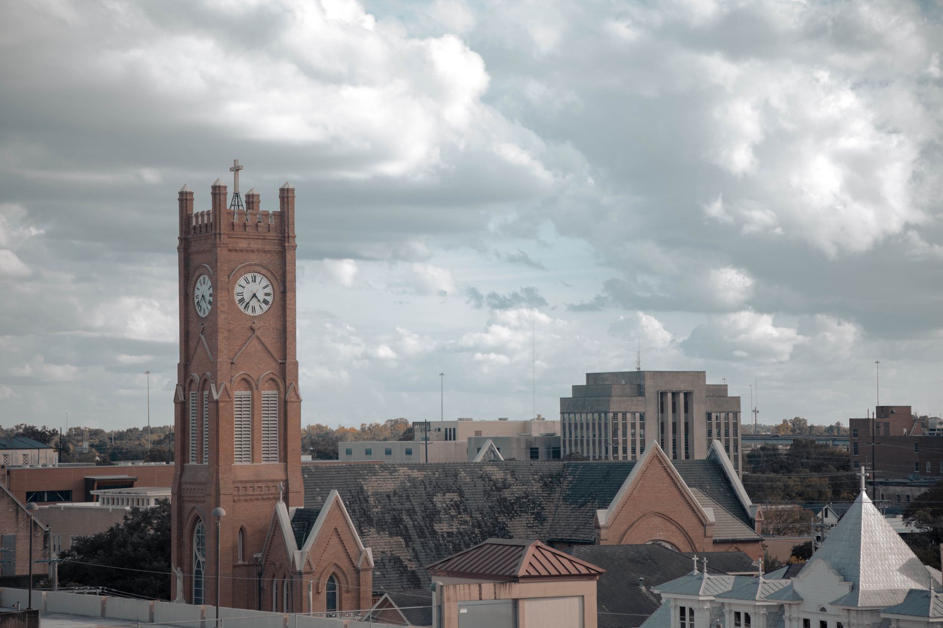 Aerial view of a historic clock tower amidst urban buildings under a cloudy sky.