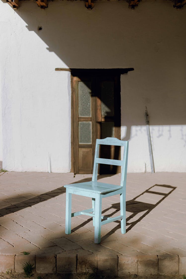 Blue Chair Standing In Full Sun In Front Of House 