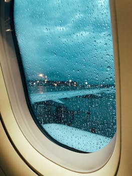 Raindrops on airplane window with tarmac view showcasing a rainy day at the airport.