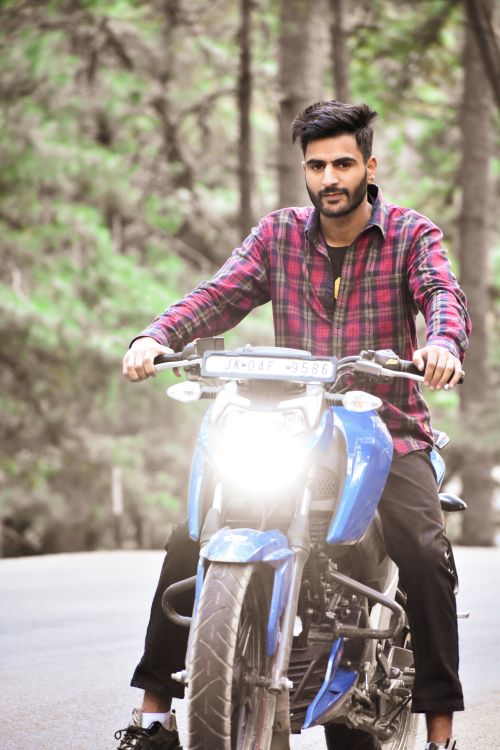 Free A young bearded man rides a motorcycle with headlights on a forest road. Stock Photo