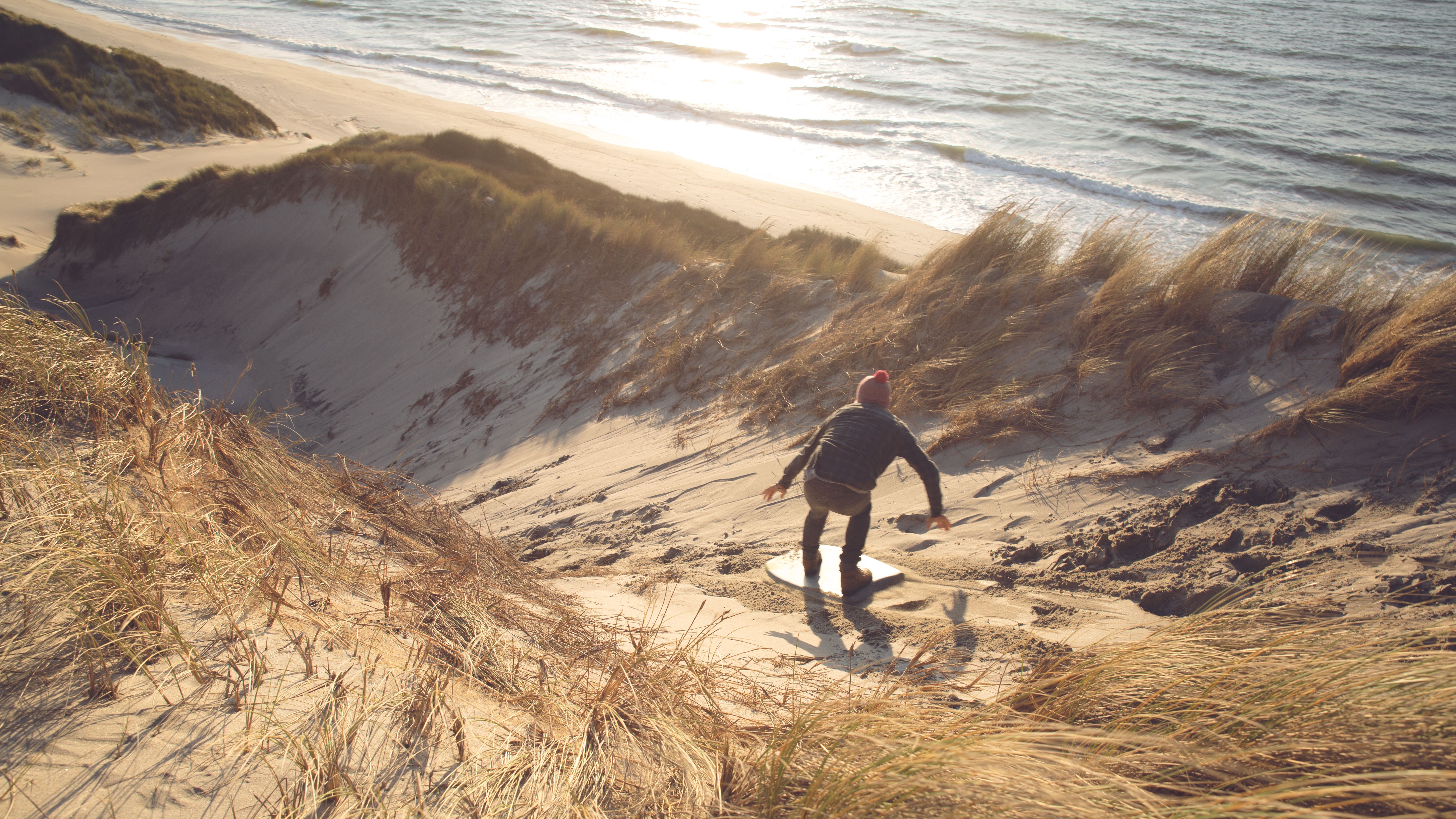 Experience thrilling sandboarding on the stunning Tasman beach dunes in New Zealand.