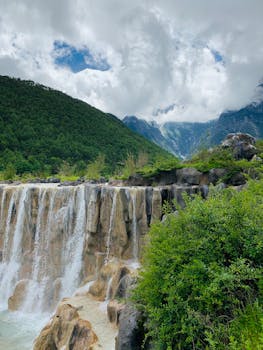 Breathtaking waterfall cascading over rocks in lush Lijiang landscape, China.