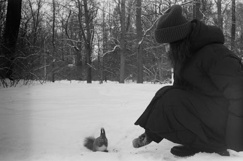 Black and White Photo of a Man near a Squirrel