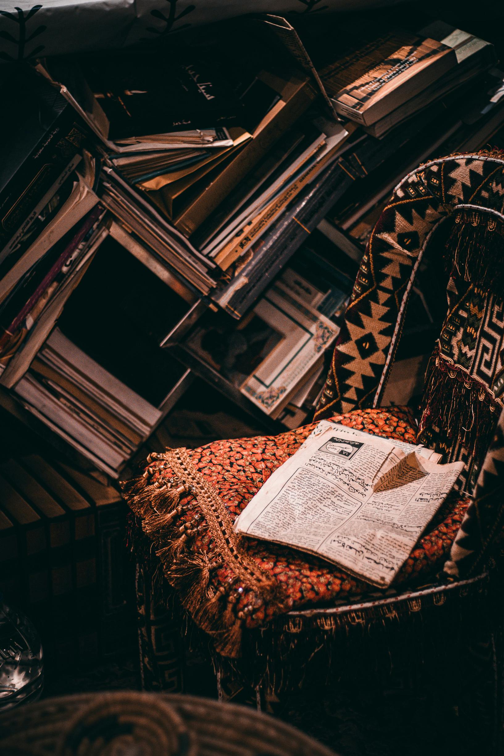 Free A warm, inviting reading nook filled with vintage books and intricate patterned textiles. Stock Photo