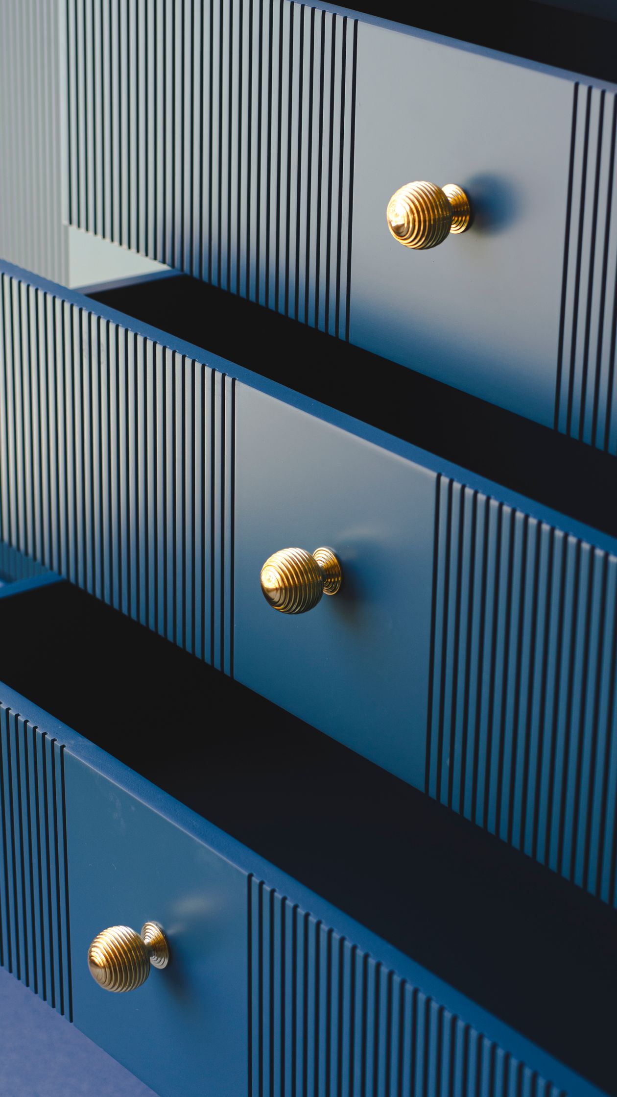 Close-up of gold beehive knobs on fluted blue drawers
