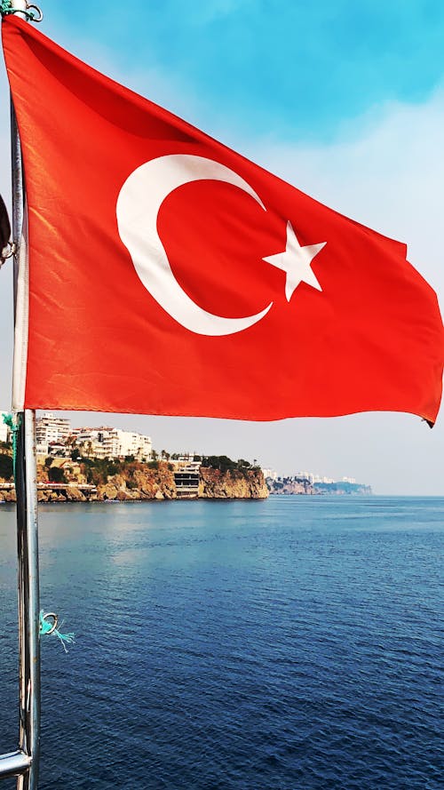 Free Flag of Turkey on Pole Near Body of Water  Stock Photo