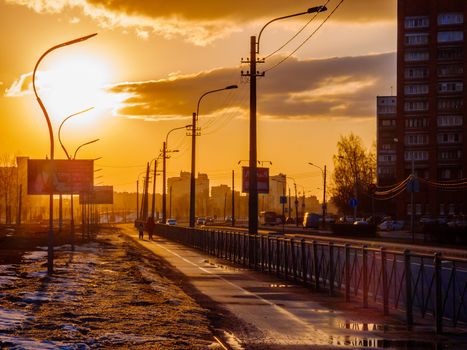 Sunset casts warm glow over urban street, highlighting sidewalks and streetlights.