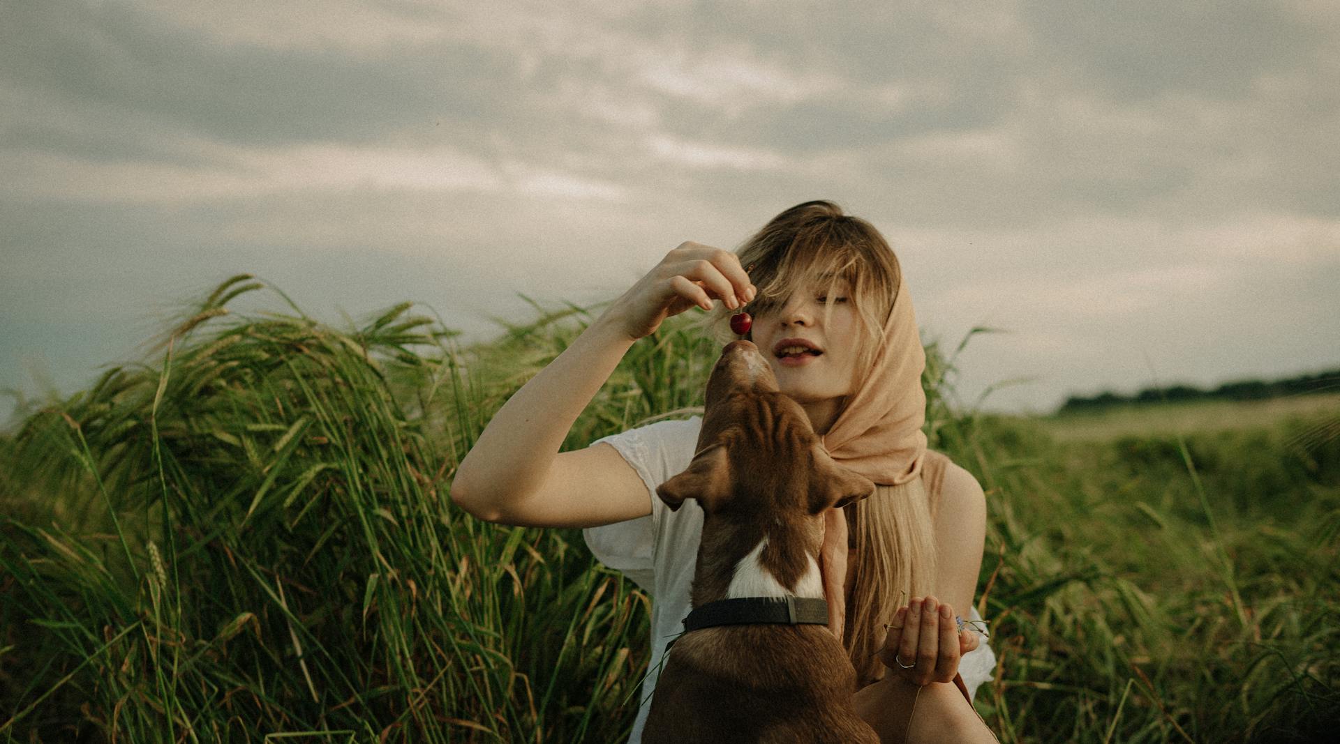 Woman Feeding a Dog with a Cherry on a Field