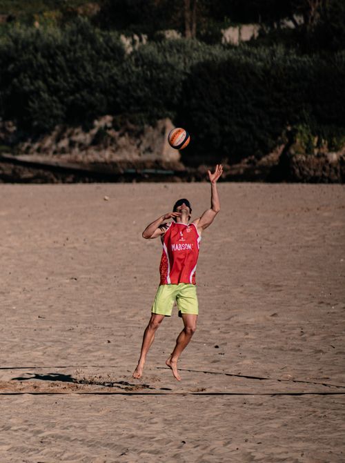 Free Man playing beach volleyball, jumping to hit the ball on a sunny day. Stock Photo