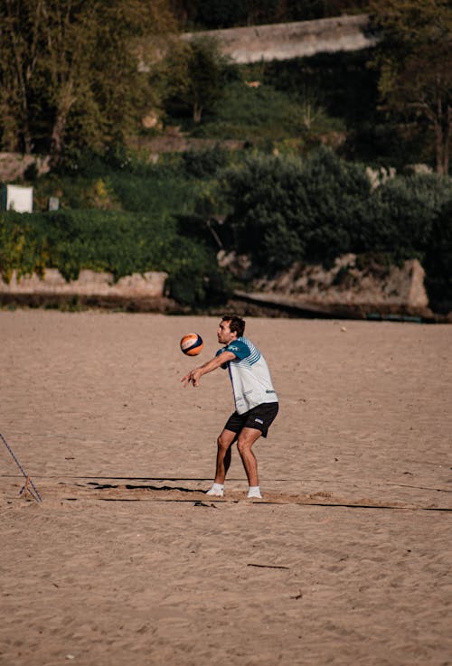 A Man in Black Shorts Playing Volleyball at the Beach