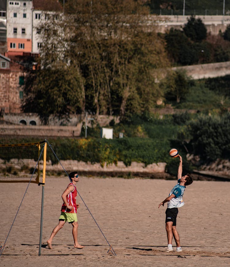 Men In Sports Wear Playing Volleyball On Beach Sand