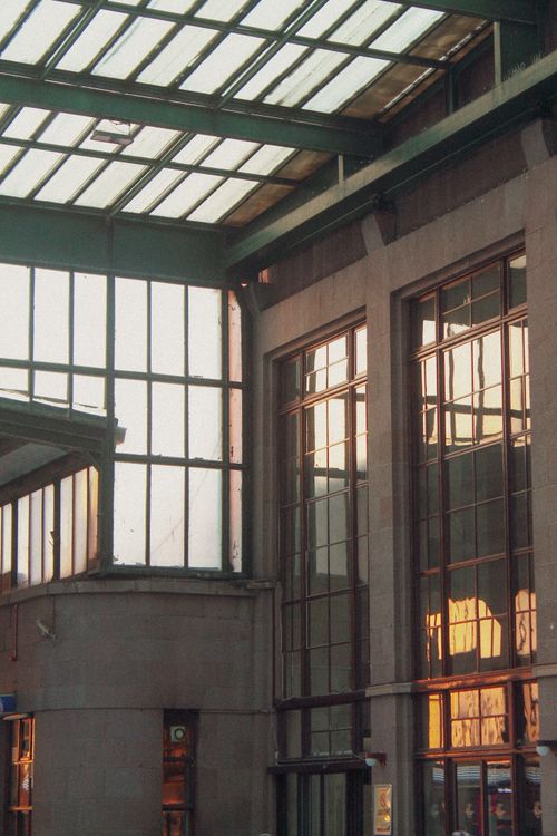 Free A modern indoor space featuring large glass windows reflecting sunlight. Stock Photo