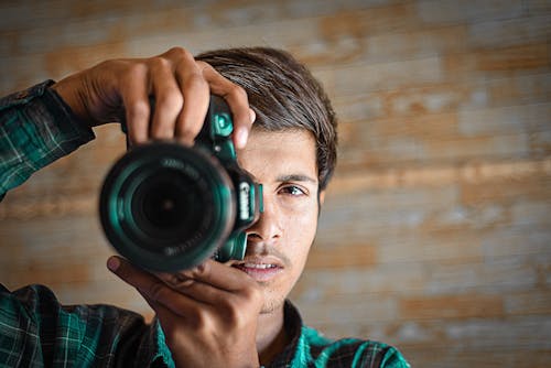 A Man in Plaid Long Sleeves Holding a Camera
