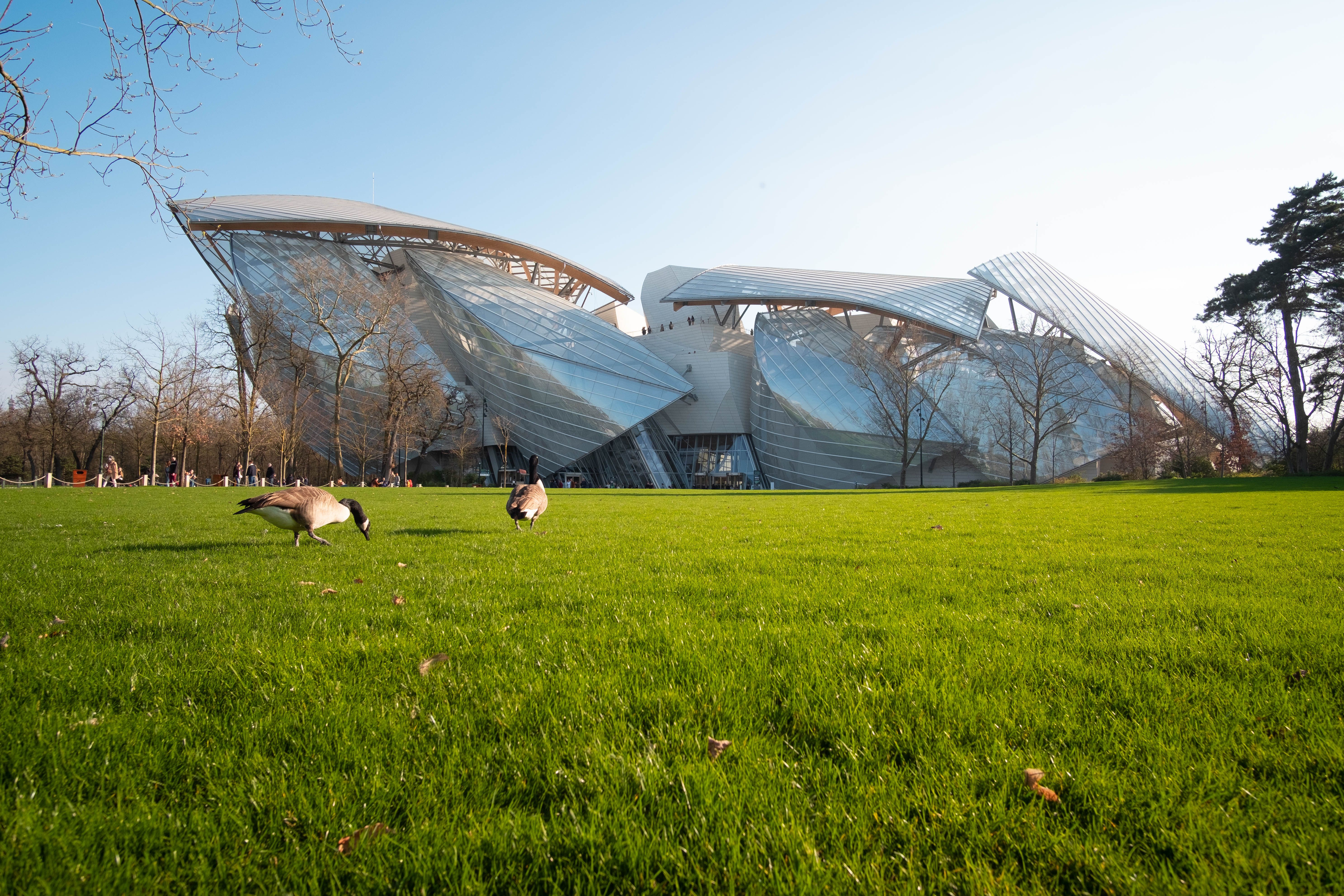 Explore the stunning architecture of the Louis Vuitton Foundation in a serene Paris park setting.