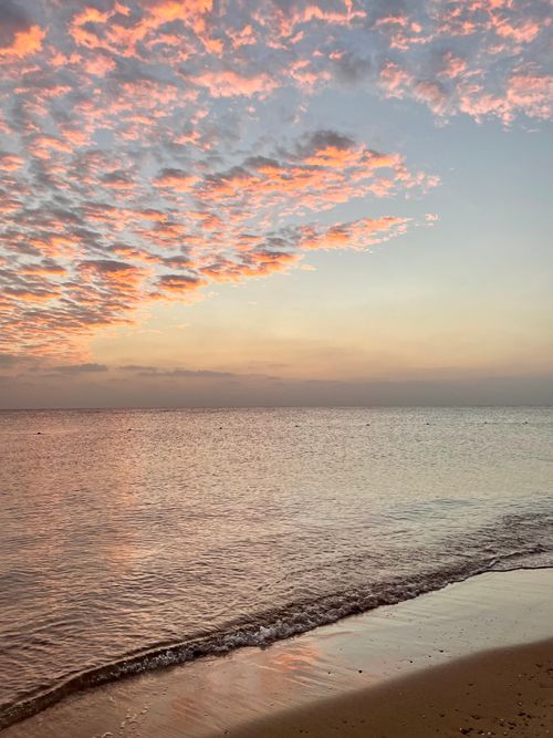 Free Peaceful beach scene at sunset with vibrant sky and gentle waves. Ideal for nature lovers. Stock Photo