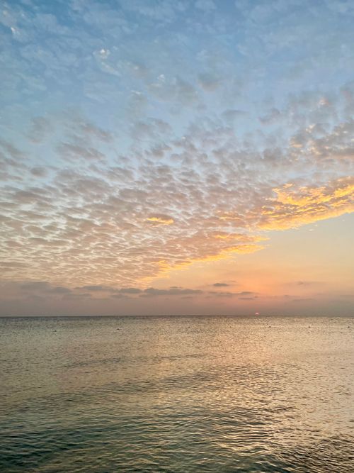 Free Serene sunset scene with a calm ocean and cloudy sky, perfect for nature imagery. Stock Photo