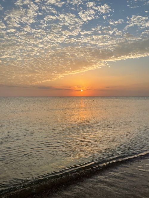 Free Beautiful sunset over the ocean with a vibrant sky and serene waves at the shore. Stock Photo