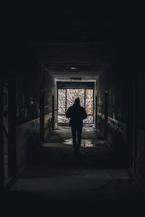 Free Back view silhouette of a person walking in a dark corridor towards light. Stock Photo