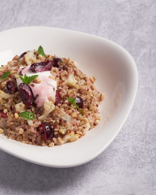 Delicious quinoa salad with cherries, mint, and pine nuts in a white bowl.