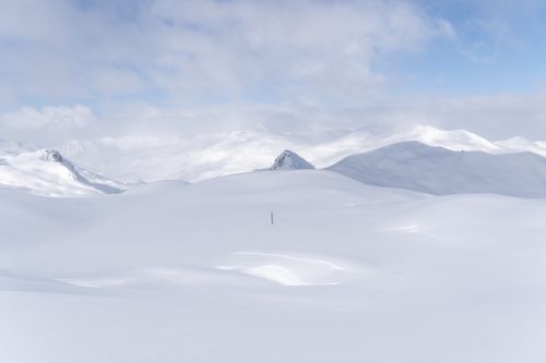 Free Expansive snow-covered mountains under a bright sky, capturing a tranquil winter scene. Stock Photo