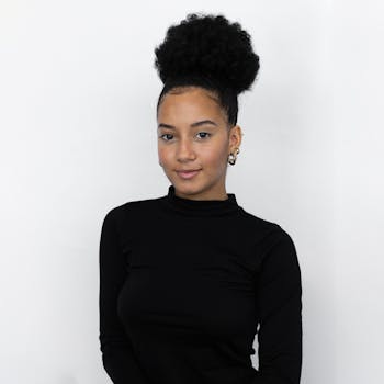 Portrait of a confident young woman with a stylish look and curly hair against a white backdrop.