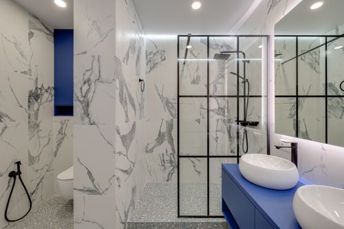 Free Elegant bathroom featuring marble walls, double sinks, and a glass-enclosed shower. Stock Photo