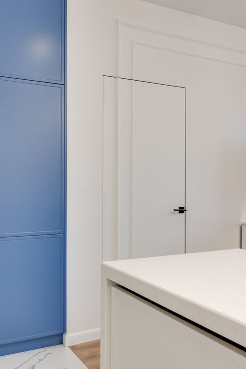 Free Modern kitchen interior featuring a sleek blue wardrobe and clean white surfaces. Stock Photo