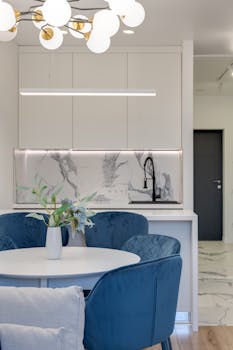 Contemporary kitchen design featuring blue chairs, round table, and marble elements.