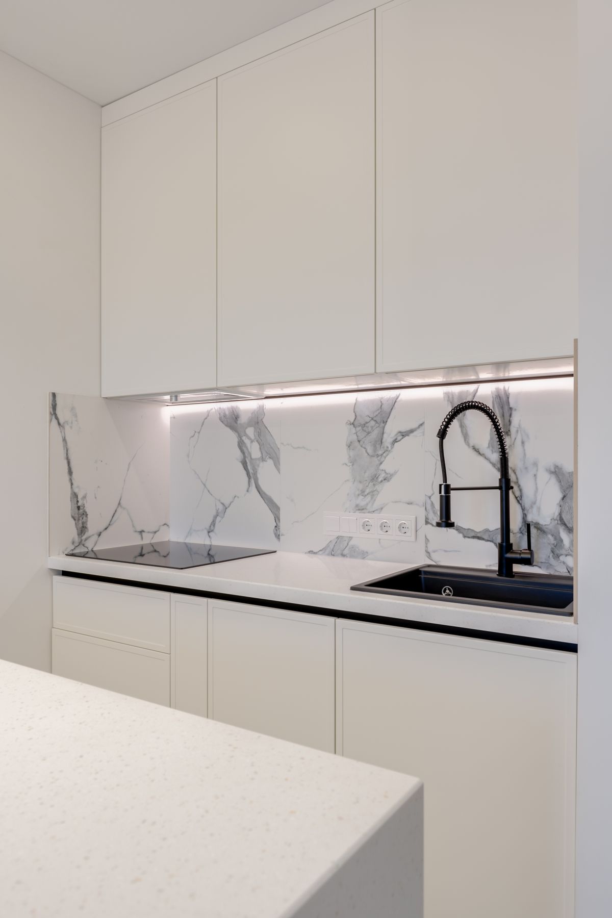 Kitchen with a stainless sink and faucet installed against a marble backsplash