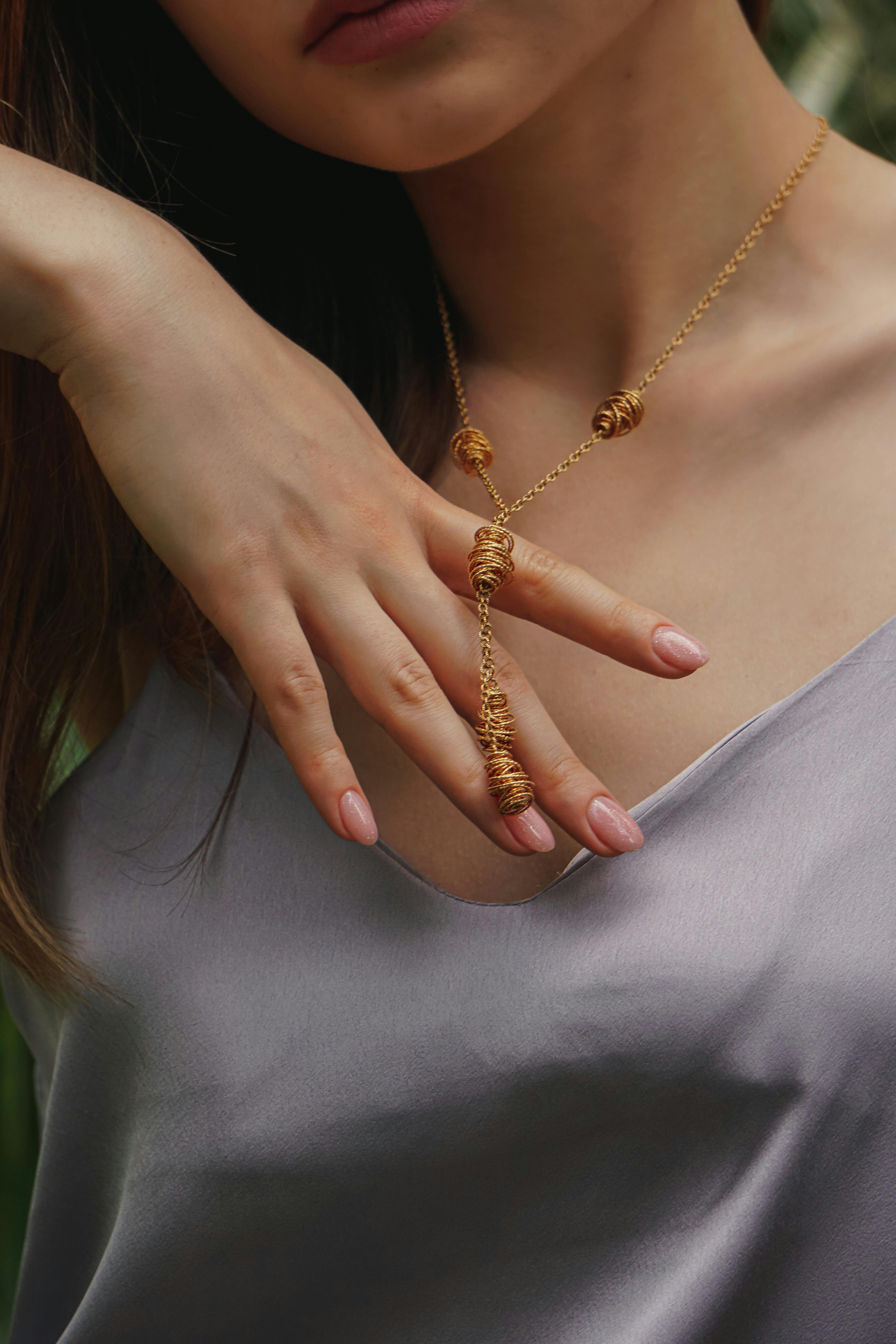 a woman in gray top wearing gold necklace