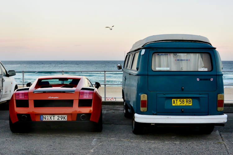 Red Lamborghini And Blue Van Parked In Front Of A Sea