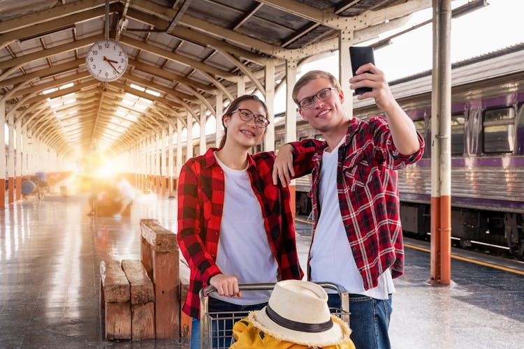 Man And Woman At The Train Station Taking A Selfie